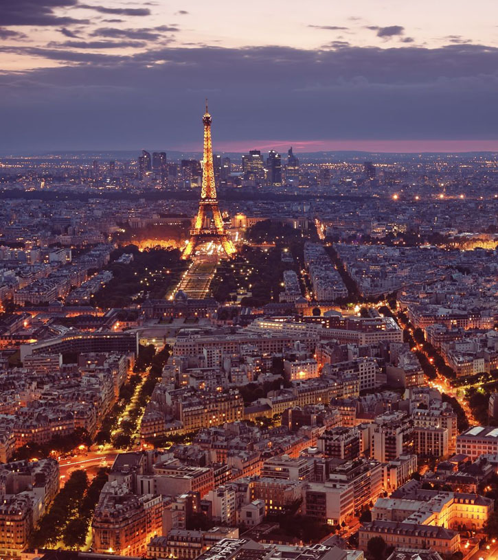 The Eiffel Tower and the streets of Paris lit up at dusk.
